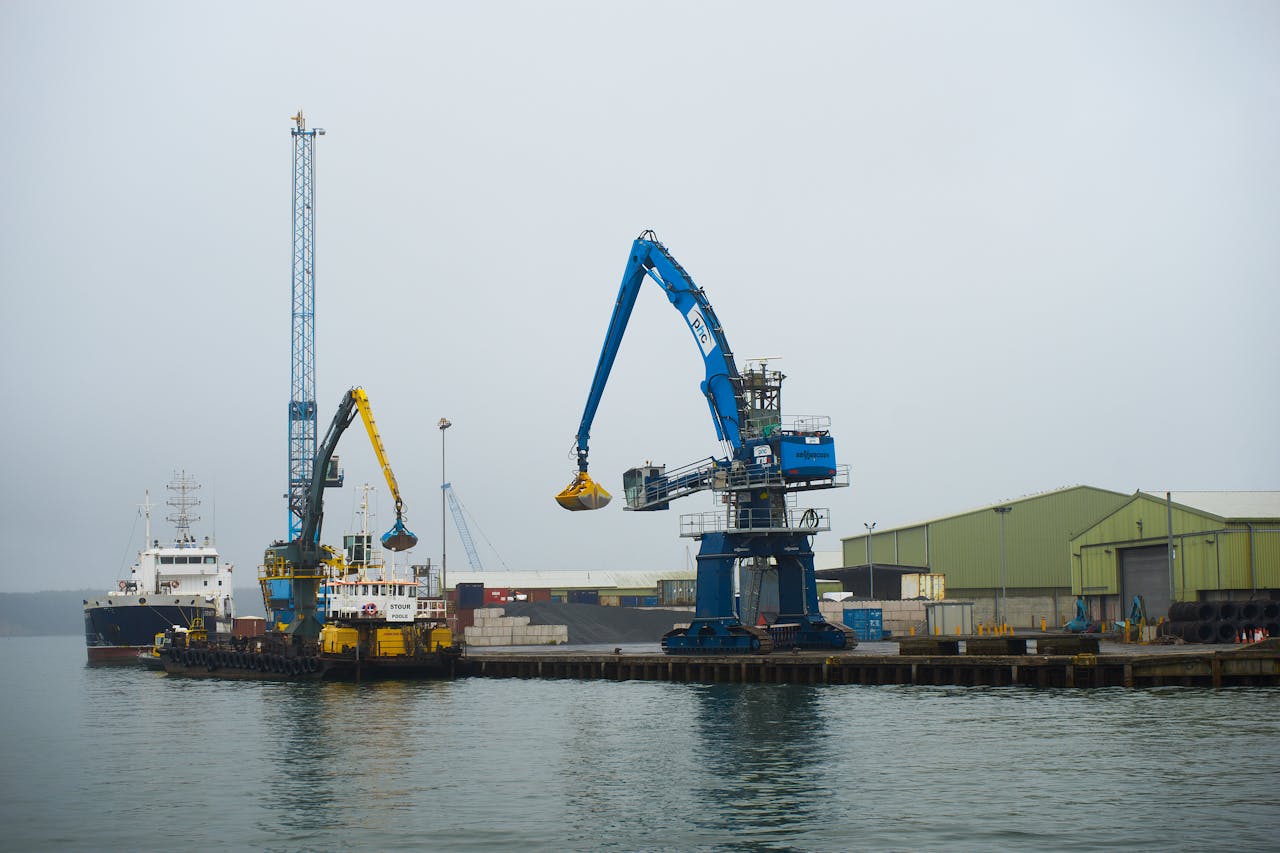 A vibrant industrial port in Poole, England, featuring cranes and barges.